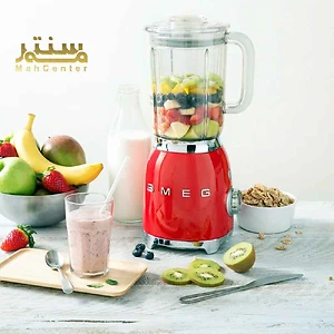 تصویر یک مخلوط‌کن قرمز SMEG است که با میوه‌های تازه مانند توت‌فرنگی، موز، کیوی و سیب پر شده است و در کنار آن مواد دیگری مانند شیر، کاسه غلات، و لیوان اسموتی آماده دیده می‌شود.